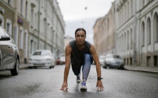Woman in activewear poised for a run on a city street, symbolizing fitness and determination.